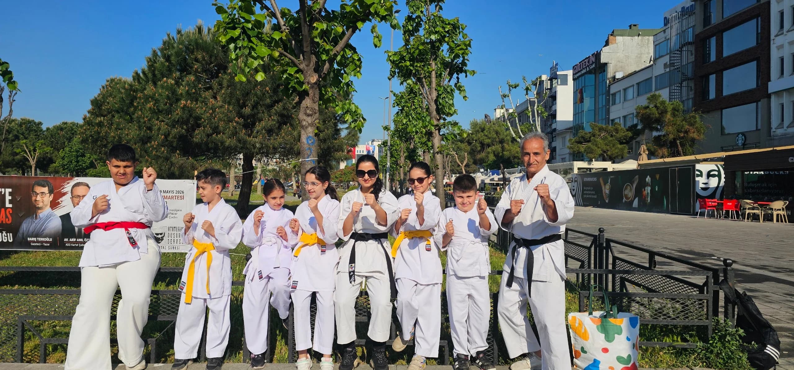Kartal Karate Akademisi ogrencileri beyaz karate kiyafetleriyle, sari, turuncu ve siyah kusaklariyla Kartal, Istanbul'da acik havada dovus durusunda