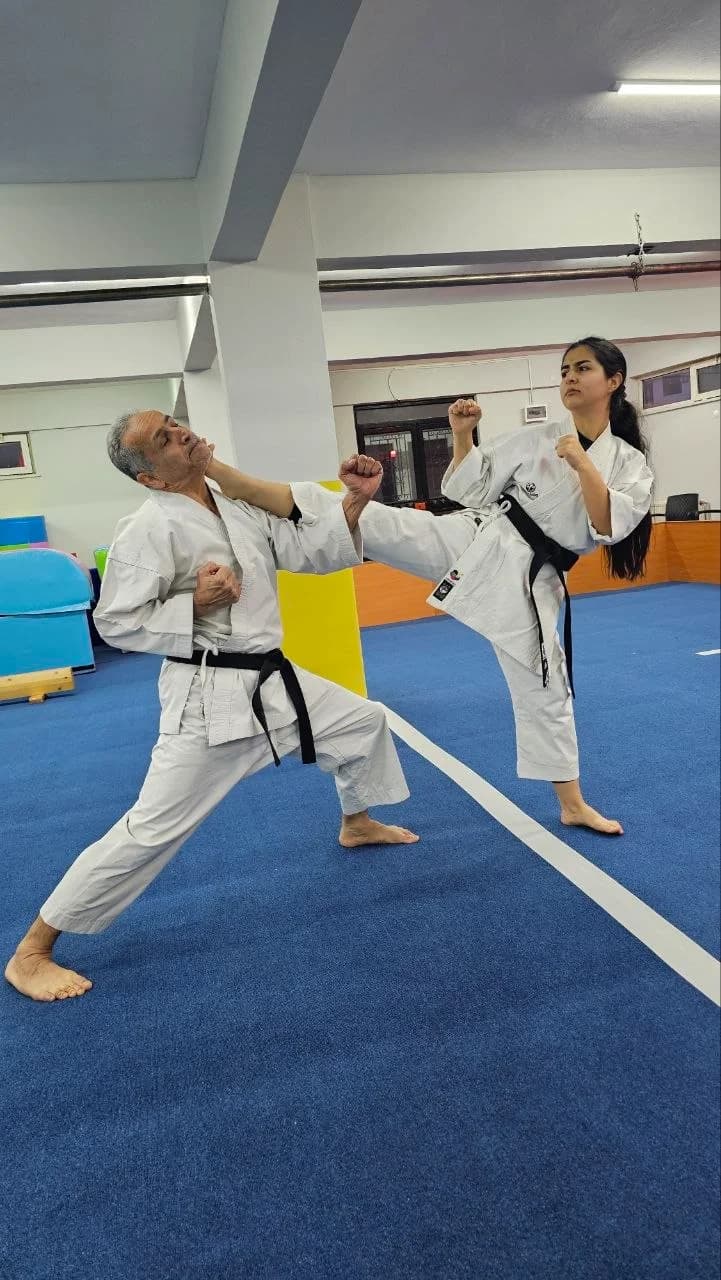 Kartal Karate Akademisi'nde siyah kusak kumite antrenmani, egitmen ve ogrenci minderde tekme teknigi calisiyor